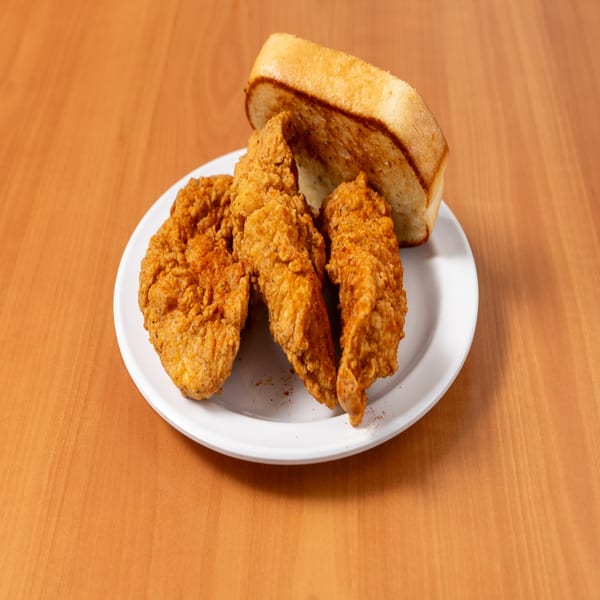 Three crispy fried chicken tenders and a slice of toasted bread on a white plate.
