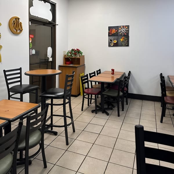 Interior of Krispi Hot Chicken with empty tables and chairs, and spice-themed wall art.