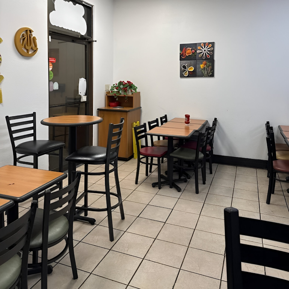 Interior of Krispi Hot Chicken with empty tables and chairs, and spice-themed wall art.