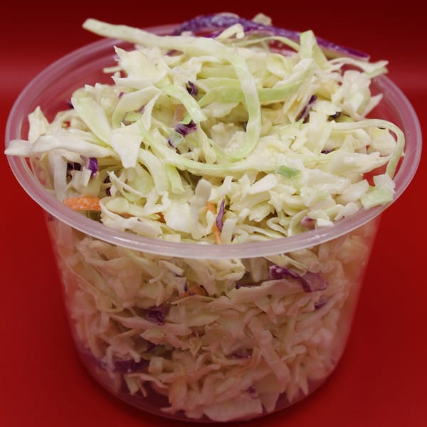 Krispi Hot Chicken's creamy coleslaw, a side dish with shredded cabbage and carrots in a clear container.