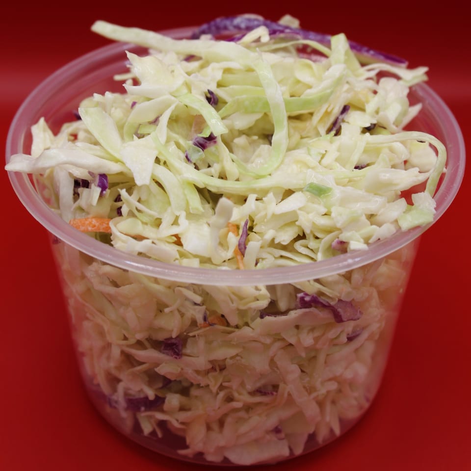 Krispi Hot Chicken's creamy coleslaw, a side dish with shredded cabbage and carrots in a clear container.