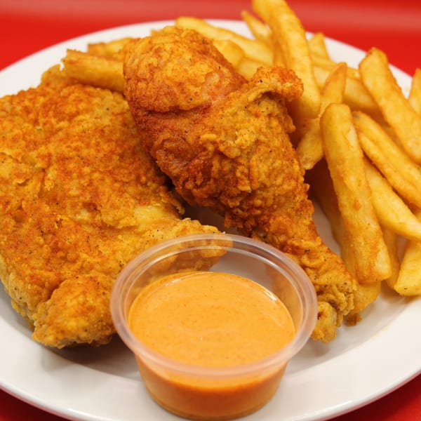 Krispi Hot Chicken fried chicken pieces, golden fries, and dipping sauce on a white plate.