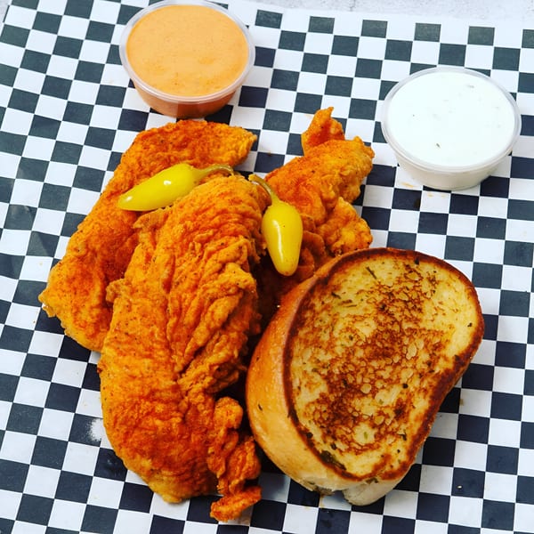Krispi Hot Chicken tenders with peppers, Texas toast, and two dipping sauces on checkered paper.