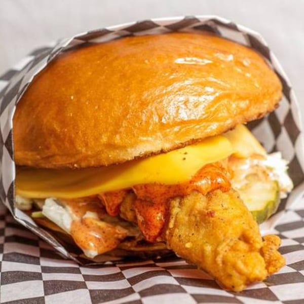 Krispi Hot Chicken sandwich with fried chicken, cheese, sauce, and pickles on a bun.