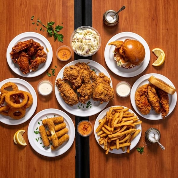 An overhead shot of a wooden table laden with various fried chicken dishes and sides.